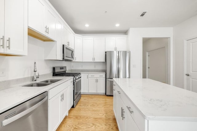 kitchen with white cabinets, sink, light hardwood / wood-style flooring, light stone counters, and stainless steel appliances