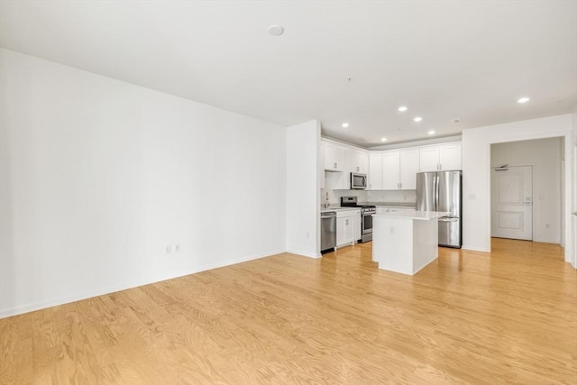 kitchen featuring white cabinetry, sink, a center island, appliances with stainless steel finishes, and light wood-type flooring