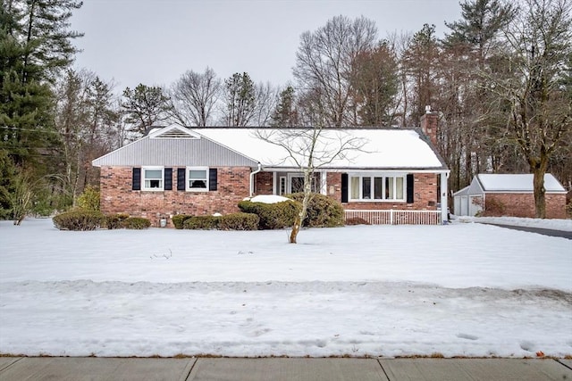 single story home with a chimney, an outbuilding, and brick siding