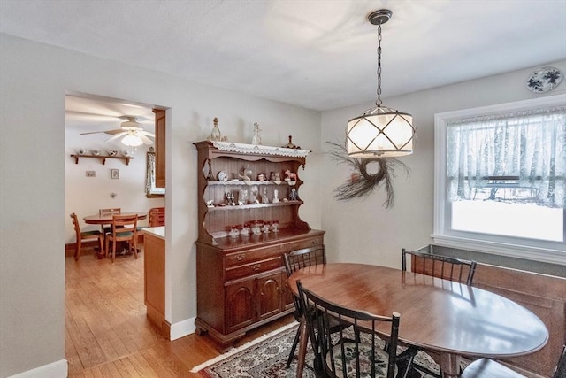 dining room with ceiling fan, light wood-type flooring, and baseboards