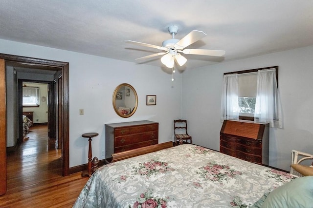 bedroom featuring ceiling fan, baseboards, and wood finished floors