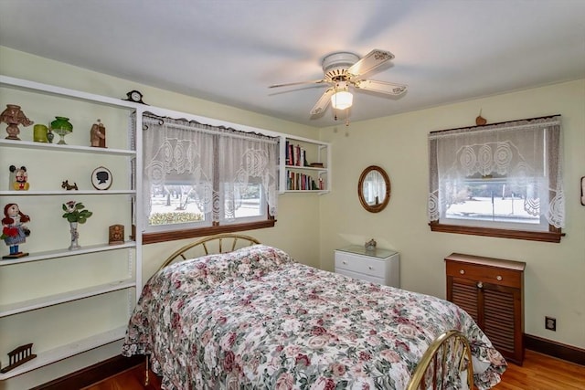 bedroom featuring a ceiling fan, baseboards, and wood finished floors