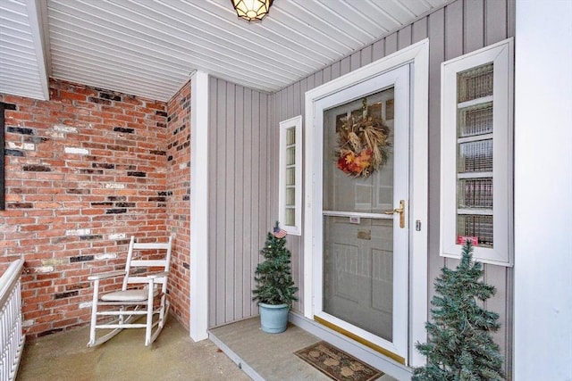 view of exterior entry featuring board and batten siding and brick siding