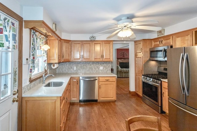 kitchen featuring light wood-style flooring, appliances with stainless steel finishes, light countertops, and a sink