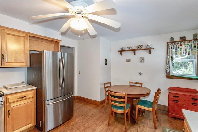 kitchen with light wood finished floors, light countertops, a ceiling fan, freestanding refrigerator, and baseboards