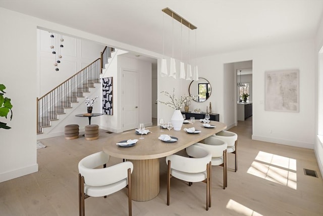dining area featuring stairs, light wood-style flooring, and baseboards