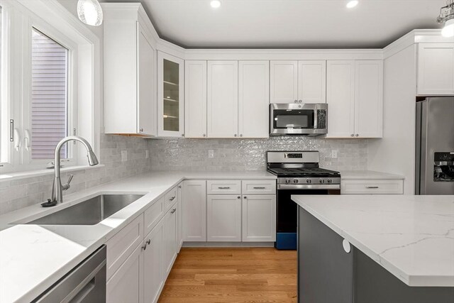 13 River St Unit 1, Danvers, MA 01923 - kitchen with white cabinets, stainless steel appliances, a sink, light stone countertops, and hanging light fixtures