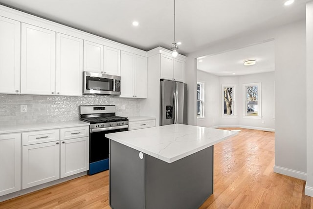 13 River St Unit 1, Danvers, MA 01923 - kitchen with appliances with stainless steel finishes, tasteful backsplash, a kitchen island, and light wood-type flooring