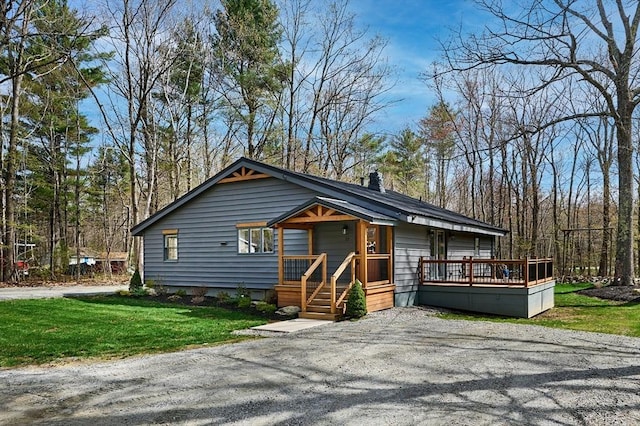 chalet / cabin with a chimney, a wooden deck, driveway, and a front yard