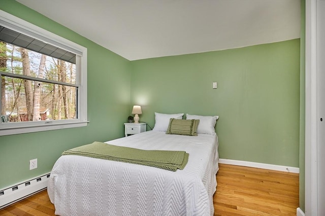 bedroom with baseboards, baseboard heating, and wood finished floors