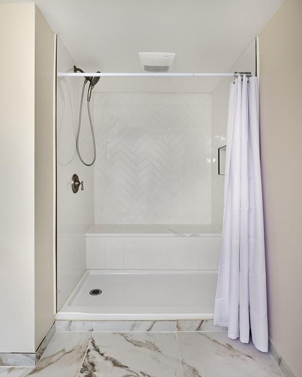 full bath with a shower with curtain and marble finish floor