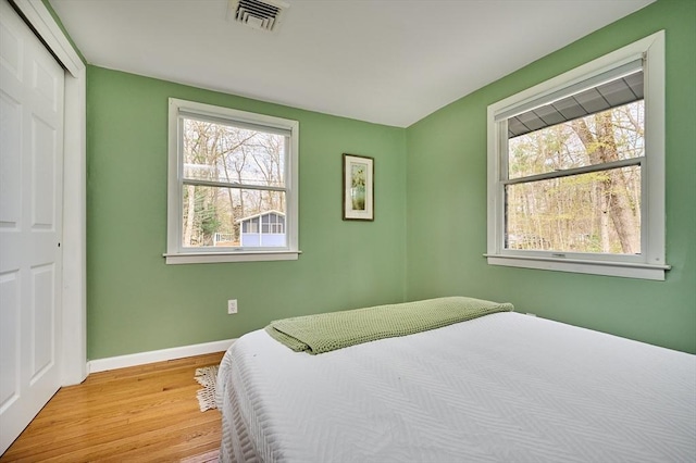 bedroom featuring baseboards, a closet, light wood-style flooring, and visible vents