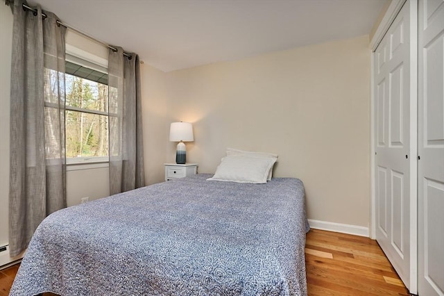 bedroom with baseboards, wood finished floors, and a closet