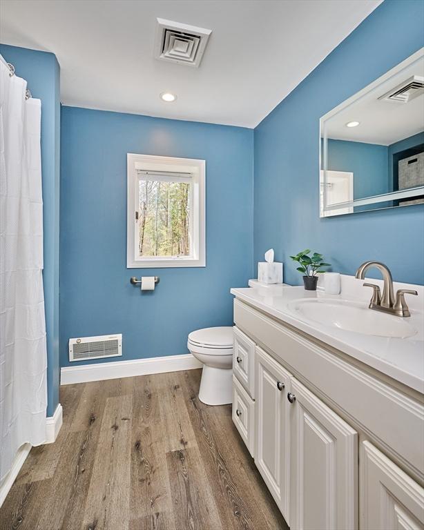 bathroom with toilet, visible vents, and wood finished floors