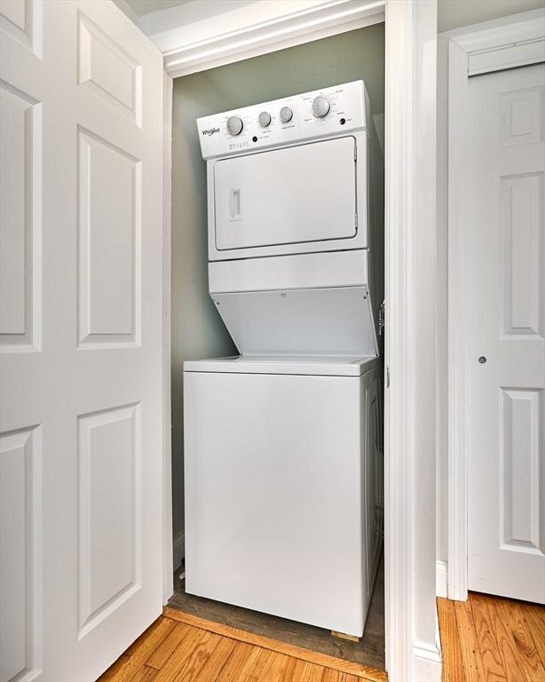 laundry room with stacked washer / drying machine, laundry area, and light wood-style floors