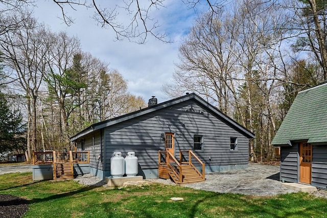 back of house with a chimney, a yard, and a deck