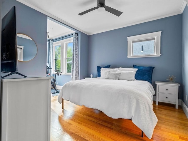 bedroom with light wood-style floors, ornamental molding, baseboards, and ceiling fan