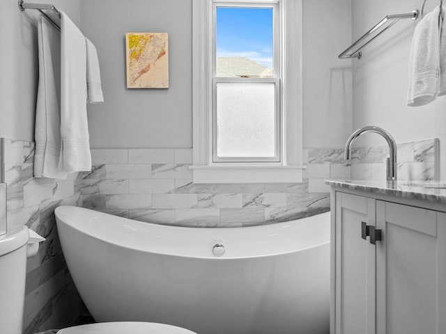 bathroom with tile walls, vanity, toilet, and a wealth of natural light