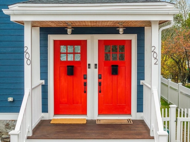 property entrance with fence and roof with shingles