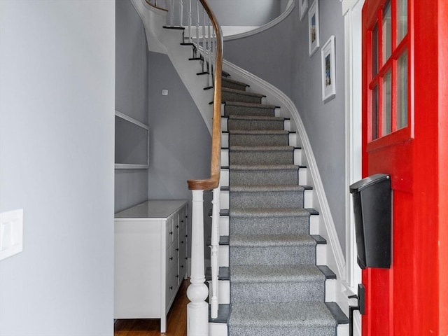 staircase with a high ceiling and wood finished floors