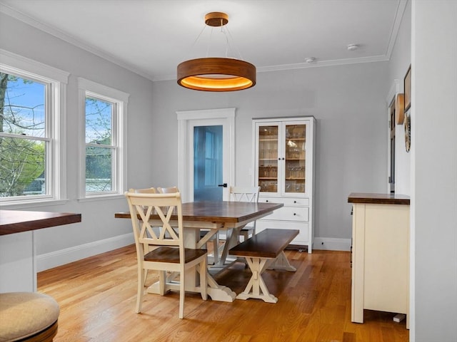 dining room with baseboards, ornamental molding, and light wood-style flooring