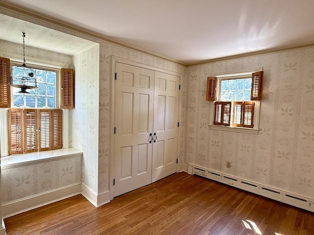 631 Elm St, Dartmouth, MA 02748 - unfurnished bedroom featuring wood finished floors, baseboard heating, crown molding, and a closet
