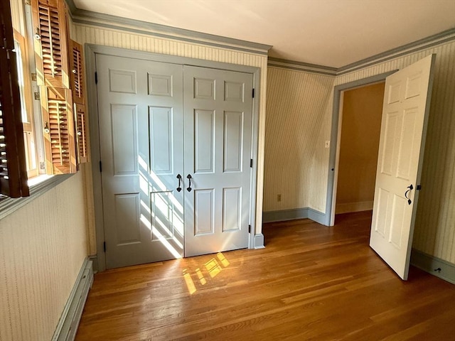 631 Elm St, Dartmouth, MA 02748 - unfurnished bedroom featuring wood finished floors, ornamental molding, wallpapered walls, a closet, and baseboard heating