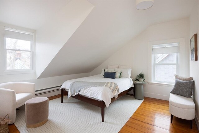 bedroom with lofted ceiling, wood-type flooring, baseboards, and baseboard heating