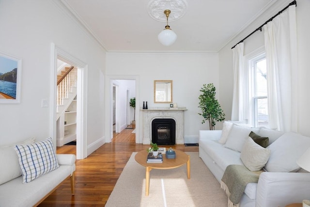 living area featuring wood finished floors, stairs, baseboards, and ornamental molding