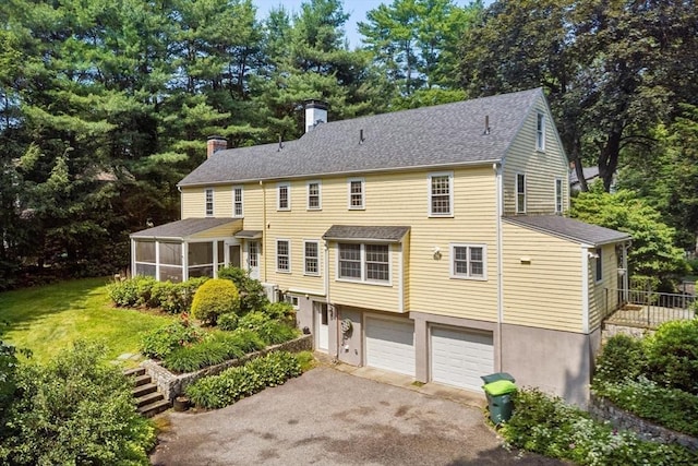 217 Conant Rd, Weston, MA 02493 - back of house featuring a chimney, asphalt driveway, an attached garage, a sunroom, and a shingled roof