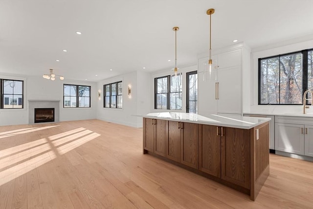 kitchen featuring a center island, sink, hanging light fixtures, plenty of natural light, and light hardwood / wood-style flooring