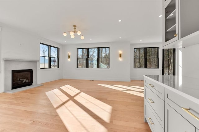 unfurnished living room with an inviting chandelier, light hardwood / wood-style flooring, and a fireplace