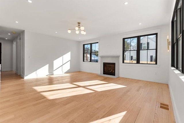 unfurnished living room with a chandelier and light wood-type flooring