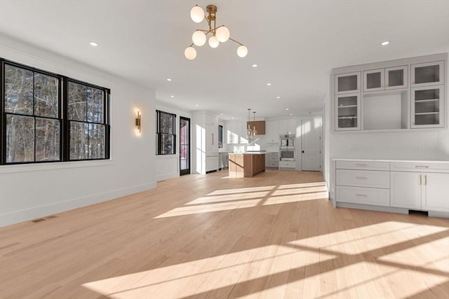 kitchen with a kitchen island, light hardwood / wood-style floors, pendant lighting, and a wealth of natural light