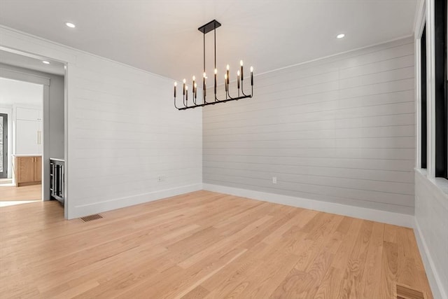 unfurnished dining area with a notable chandelier and light hardwood / wood-style floors