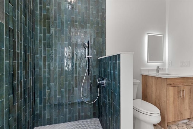 bathroom featuring a tile shower, toilet, and vanity