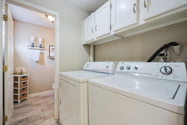 laundry room with baseboards, light wood finished floors, cabinet space, and washer and dryer
