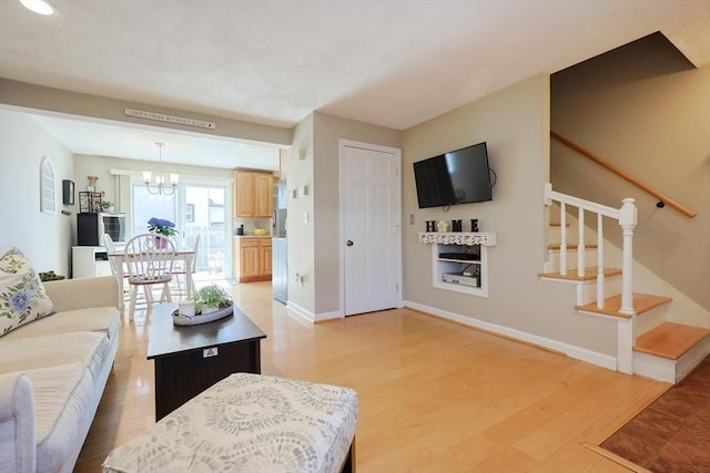 living area featuring baseboards, a chandelier, and stairway
