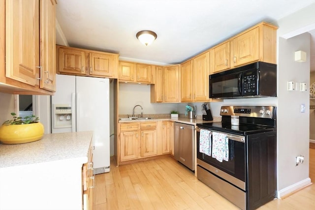 kitchen with light brown cabinetry, appliances with stainless steel finishes, a sink, and light countertops