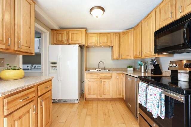 kitchen featuring a sink, light countertops, stainless steel appliances, light wood-type flooring, and washing machine and dryer