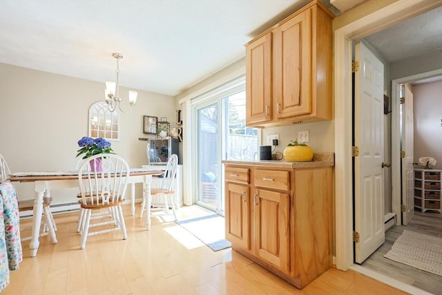 kitchen with baseboard heating, light countertops, an inviting chandelier, light brown cabinets, and light wood-style flooring