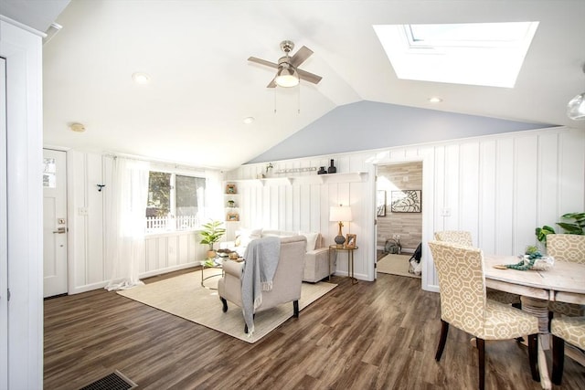 living room featuring dark wood-type flooring, lofted ceiling with skylight, and ceiling fan