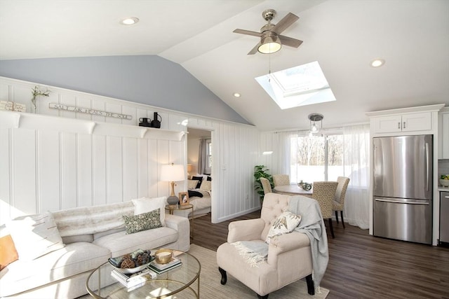 living room featuring lofted ceiling with skylight, dark hardwood / wood-style floors, and ceiling fan