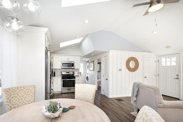 dining room with a wealth of natural light, lofted ceiling with skylight, dark hardwood / wood-style floors, and ceiling fan