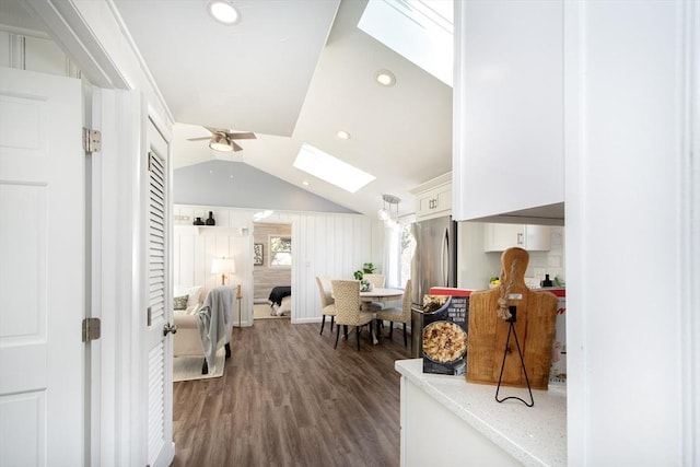 interior space with dark hardwood / wood-style flooring, lofted ceiling with skylight, and ceiling fan