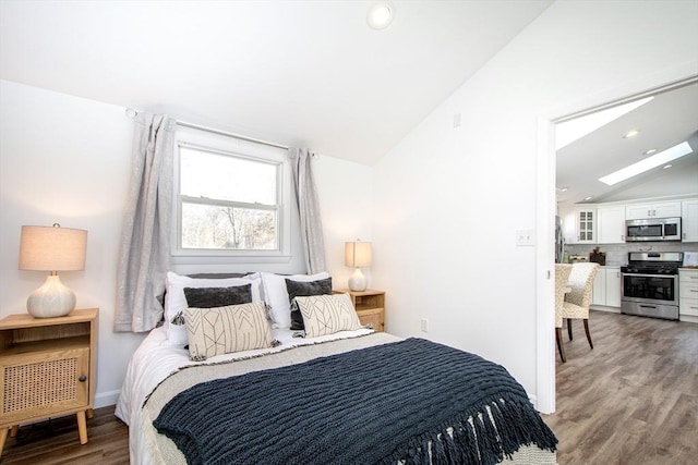 bedroom with vaulted ceiling, wood-type flooring, and stainless steel refrigerator