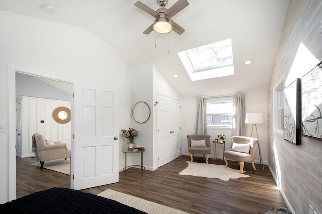 sitting room featuring lofted ceiling with skylight, dark hardwood / wood-style floors, and ceiling fan