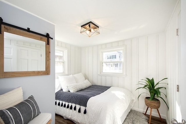 bedroom with hardwood / wood-style flooring and a barn door