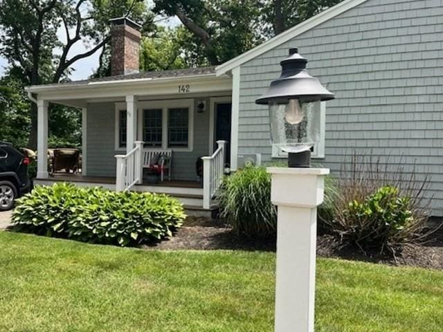 property entrance with a yard, a porch, and a chimney