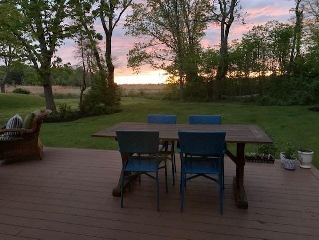 wooden deck featuring outdoor dining area and a lawn